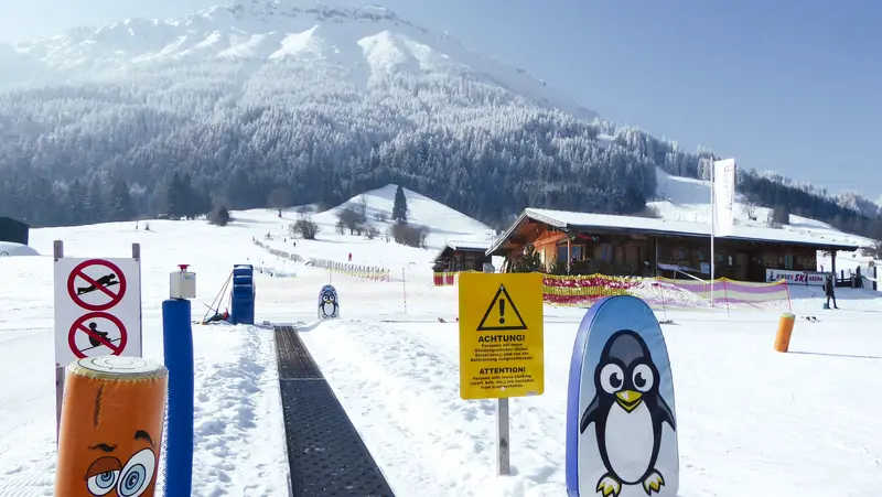 Förderband an der Skipiste mit einer verschneiten Landschaft im Hintergrund.