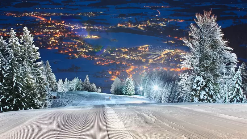 Blick über die beleuchtete Skipiste beim Flutlichtfahren in Pfronten-Steinach mit einem schönen Blick ins Tal.