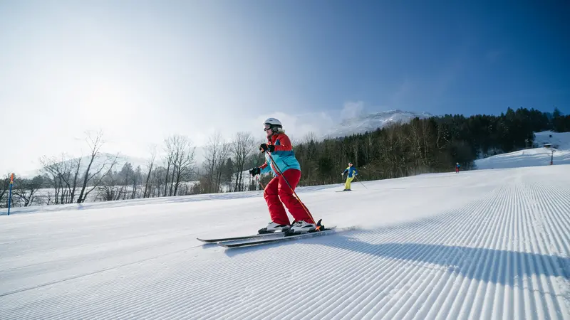 Skifahrer auf der Piste, im Hintergrund eine verschneite Landschaft.
